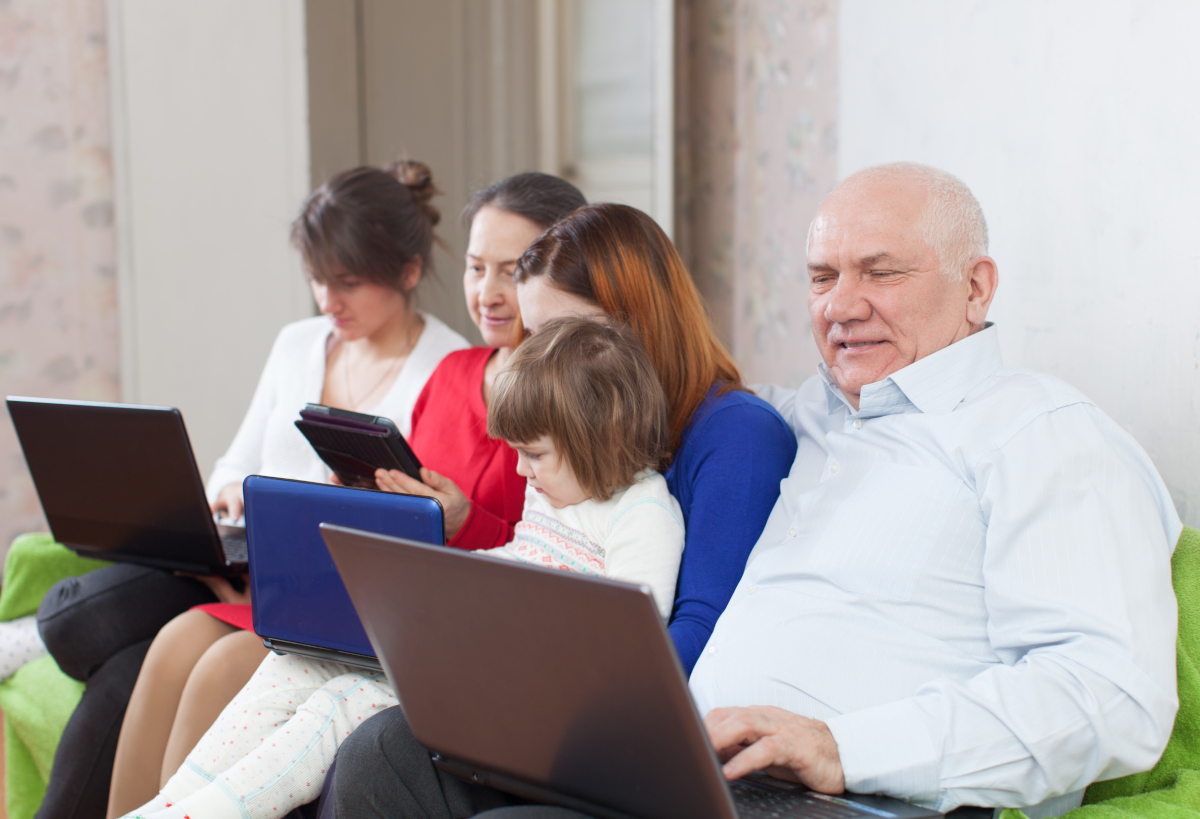 Multi-generational family with laptops seating on a sofa