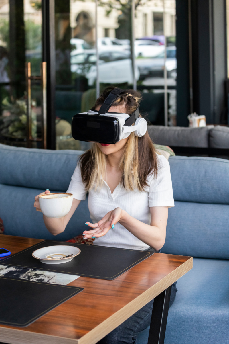 Young girl with VR set in a cafe, with cup of coffee